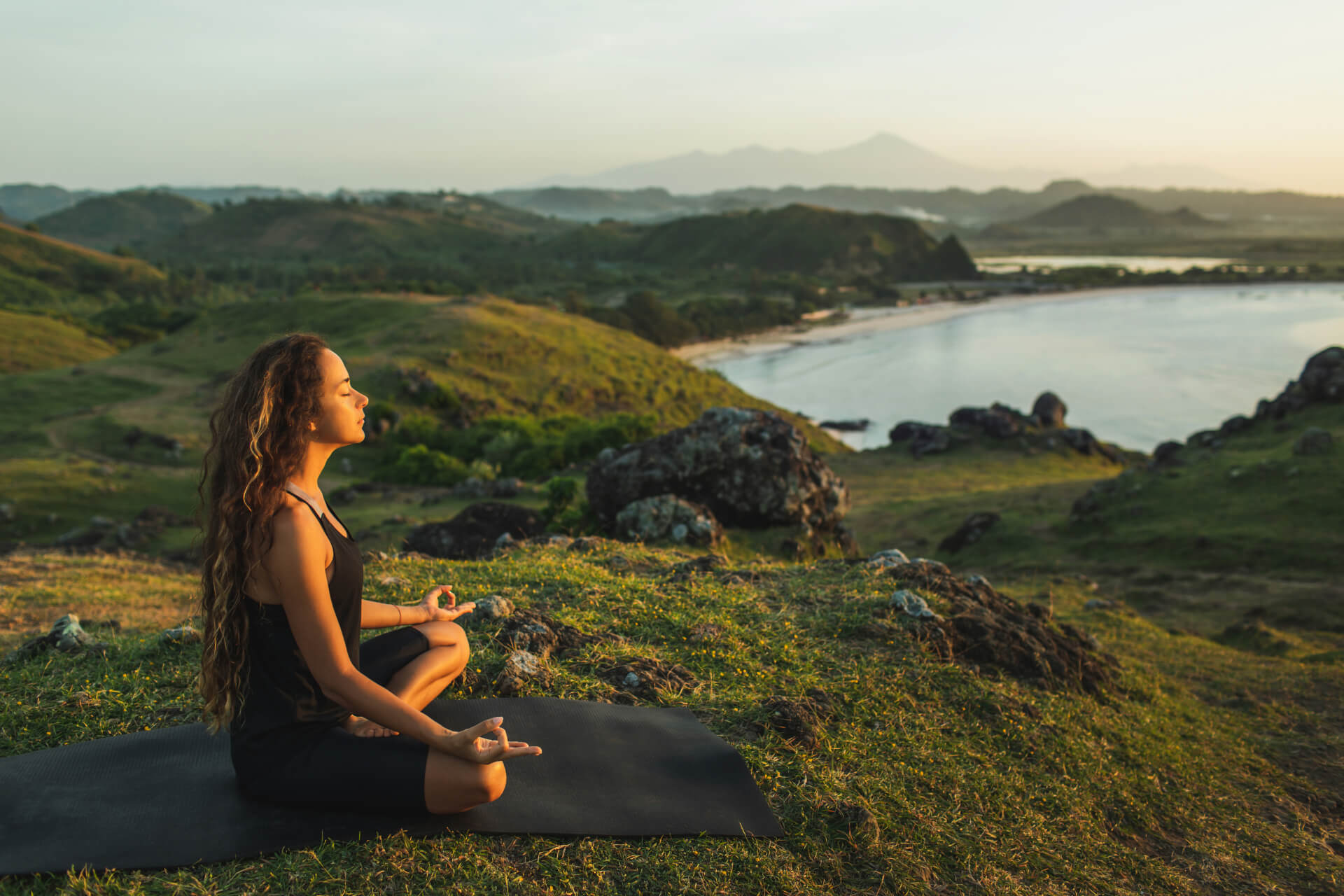 Spiritual woman meditating on mountain top with lake in background